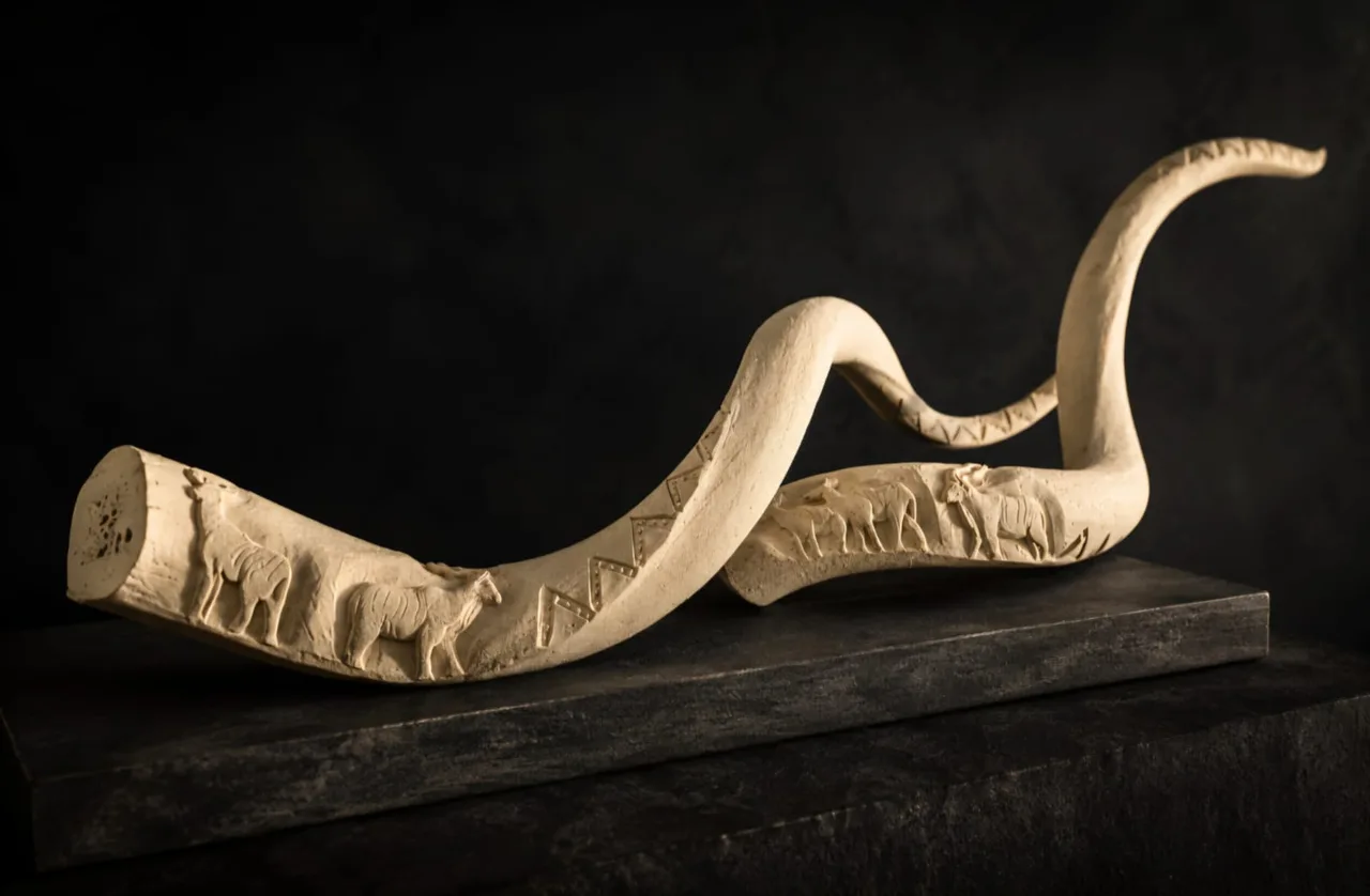 Pair of kudu inner horns carved with a frieze of animals and a zigzag border