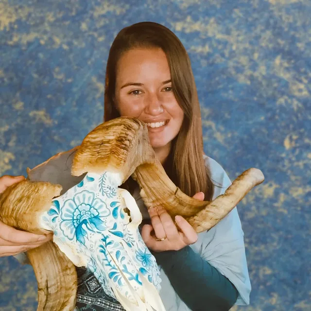 Alta van Niekerk holding one of her hand-painted skulls, finished in a blue floral pattern