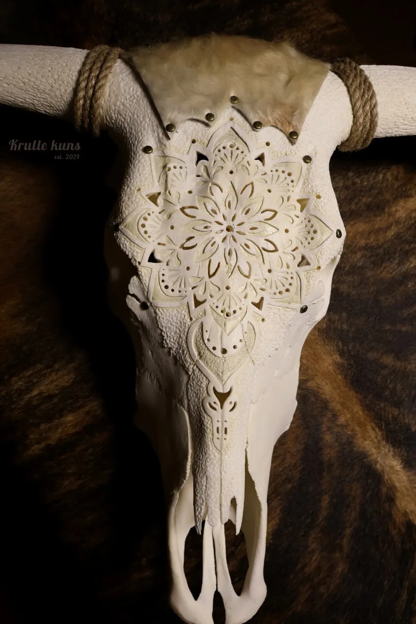 Ox skull carved with a pierced mandala, with brass studs, rope-wrapped horns and cowhide at the crown