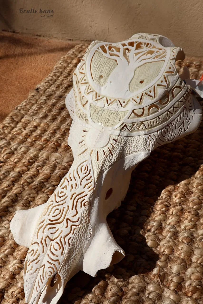 Warthog skull carved with a tree at the crown and flowing patterns down the snout, on a woven mat